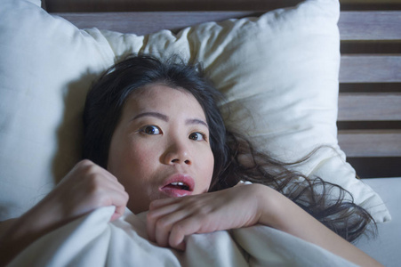 年轻的恐惧和紧张的生活方式的夜肖像亚洲华人妇女躺在床上遭受噩梦的恐惧和惊恐抓住毯子覆盖她的恐怖脸表情
