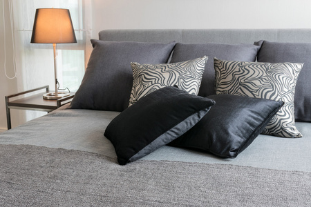 sylish 卧室室内设计与黑色图案枕头在床上和装饰台灯
