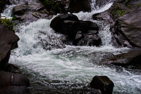 在山石之间的水流。秀丽的山小河小河以快速的流动的水和岩石。水流在美丽的风景里。风景如画的急流在河上