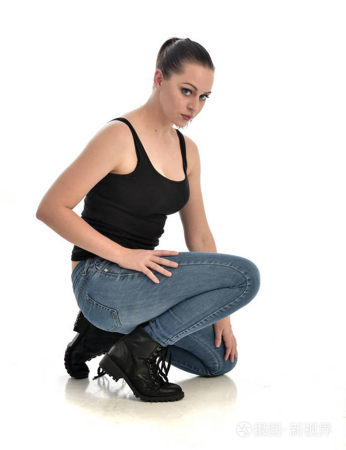 穿黑色单和牛仔裤的黑发女孩的全长肖像.坐姿.