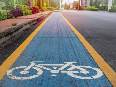 自行车车道。白色自行车图标在蓝色和黄色背景上老路在村庄