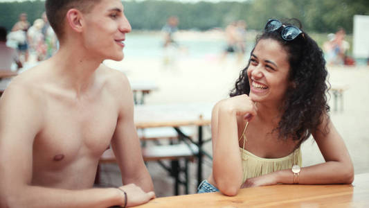 两个男人和女人约会的湖泊, 户外。年轻的女孩和男人坐在长椅上说话。夏日爱情