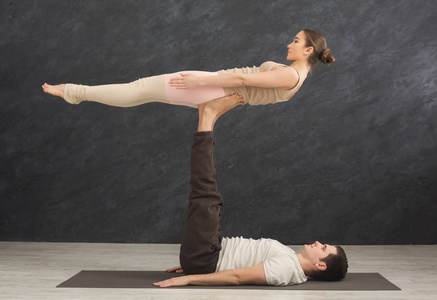 年轻夫妇在垫子上练习 acroyoga