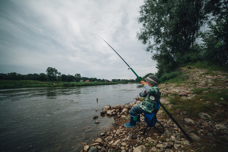 男孩在河岸边捕鱼