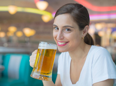 年轻漂亮的女人喝一品脱啤酒到美国餐厅