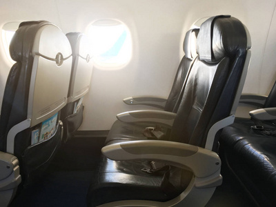在商用机舱的过道上, 有一排黑色的真皮座椅和照明窗。经济舱飞机座椅。背景, 复制空间, 关闭