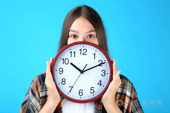 年轻女孩拿着一个蓝色的背景时钟