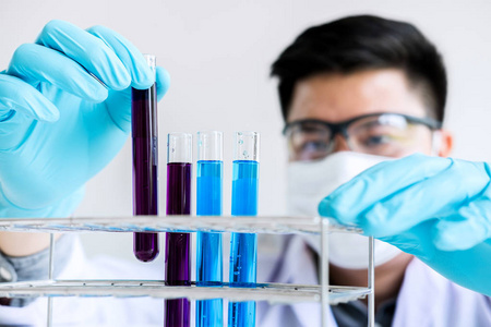 生物化学实验室研究, 科学家或医学在实验室涂层持有测试管与试剂与色液滴在实验室工作的玻璃设备