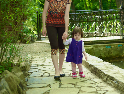 宝贝女孩和她的母亲在公园散步蓝色的连衣裙