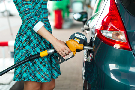 女人将填充到她的车在一个加油站的汽油照片