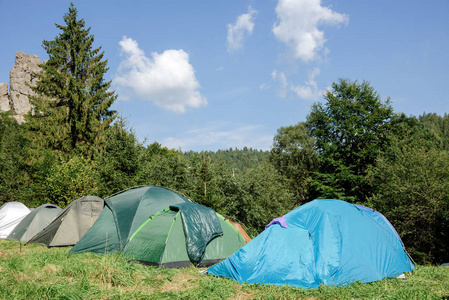 日出时在绿色草地上的旅游帐篷。露营背景