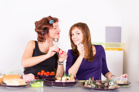 两个年轻漂亮的女人家庭主妇烹饪用睫毛夹头发
