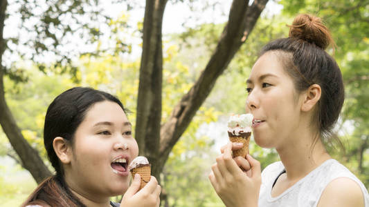两个人胖可爱的女孩吃冰淇淋与感觉美味