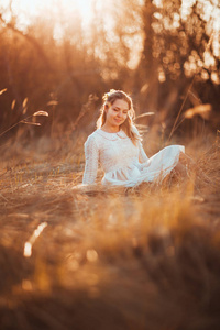 女孩坐在田野上的夕阳背景
