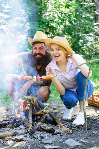 情侣在篝火旁露营森林烧烤香肠。传统的烘焙食品作为野餐的属性。野营和野餐。夫妇饥饿的游客烤香肠在棍子自然背景