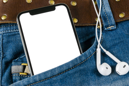 智能手机在牛仔裤口袋里用耳机隔离的白色屏幕。具有复制空间的商务工作场所。文本的空白。用于模拟的隔离屏幕