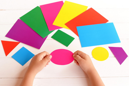 孩子们颜色和几何形状.达到概念.不同的纸板卡片在桌上照片