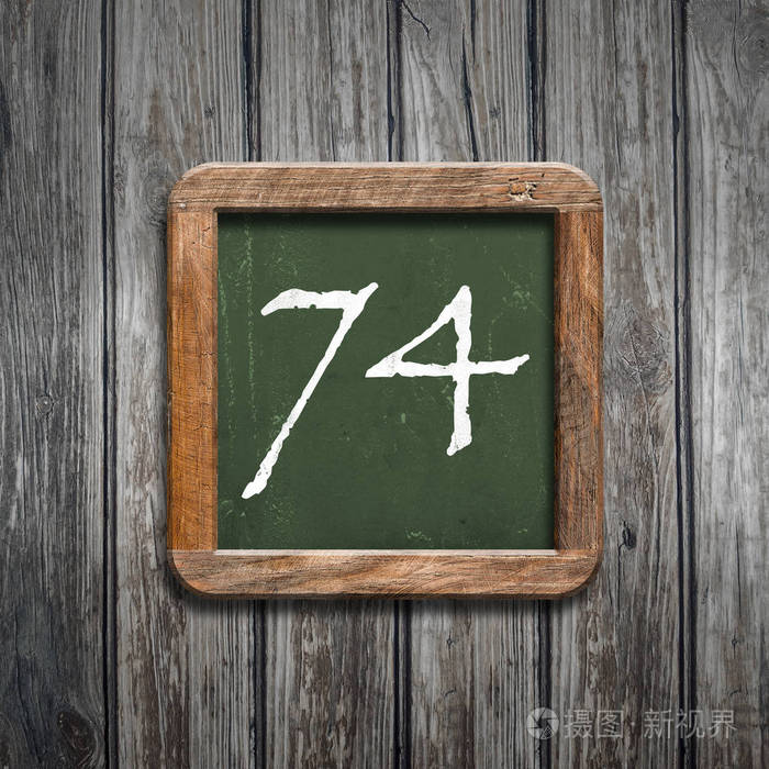 数字74在绿色黑板在木背景之上
