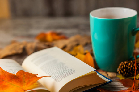 秋天。一本开放的书。杯茶, 咖啡, 可可。黄红色的叶子。木质背景