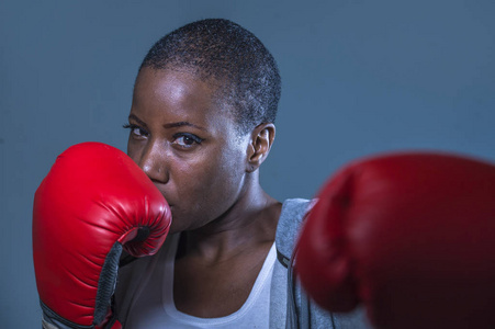 关闭脸上的年轻愤怒和挑衅黑人美国运动妇女在拳击手套训练和假扮成一个危险的战斗机在健身健身房和战斗锻炼概念