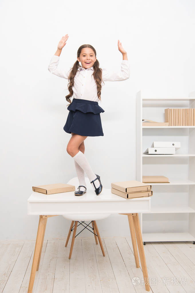 小学生庆祝完学业, 女孩学校制服快乐欢快的舞蹈在桌上.
