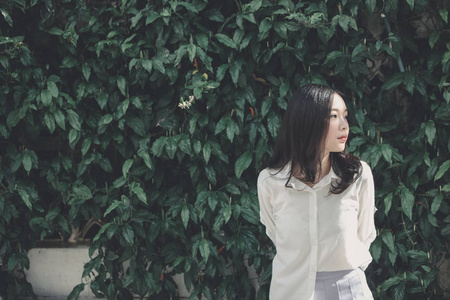 亚洲女孩的肖像白色衬衫和裙子看着微笑在户外自然复古电影风格