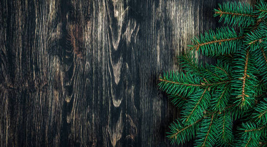 云杉树枝上的黑色老式木质背景。圣诞理念