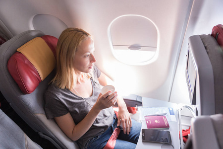 在飞行期间在商业乘客飞机上喝咖啡的妇女