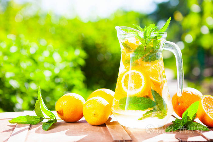 夏季新鲜冷饮饮料.冰柠檬水在水罐和柠檬和橙色与薄荷在桌外面.