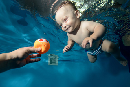 快乐宝贝水下游泳池里对玩具，微笑和大笑。肖像。特写