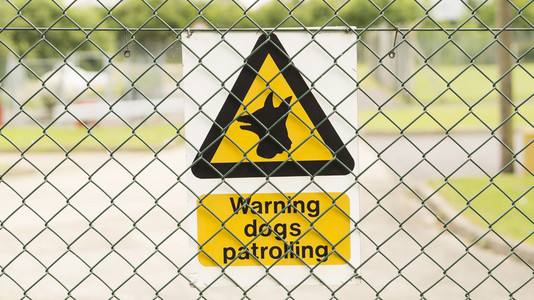 篱笆上的标志警告 巡逻的狗