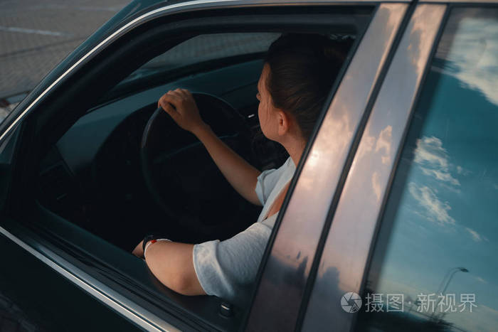 穿着便装的年轻女子开车时把头伸出窗外.