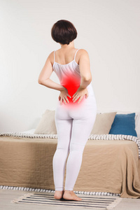 背部疼痛, 肾脏炎症, 妇女在家里患背痛, 疼痛地区突出红色
