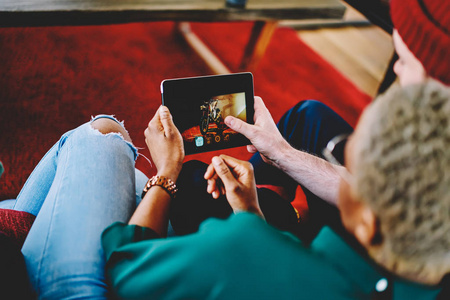 被裁剪的夫妇在爱一起观看视频在博客上的现代触摸板设备使用4g 互联网连接。男性和女性在社交网络上观看数码片的照片