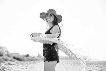 黑白图像的年轻迷人的时尚女人戴草帽在海滩上玩得开心。旅游和旅游概念