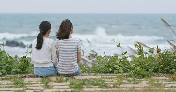 亚洲妇女聊天和坐在海边