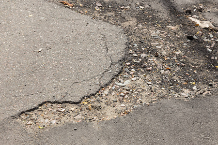 与凹坑造成的损坏的沥青路面道路冻结区域和解冻周期在冬季