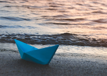 在日落时, 纸蓝色的船被扔在湖的沙滩上。海滩假期