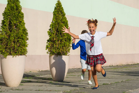 笑学童一个女孩和一个男孩在校园里快乐地奔跑着。