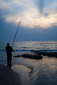 早晨在海边钓鱼的人的剪影