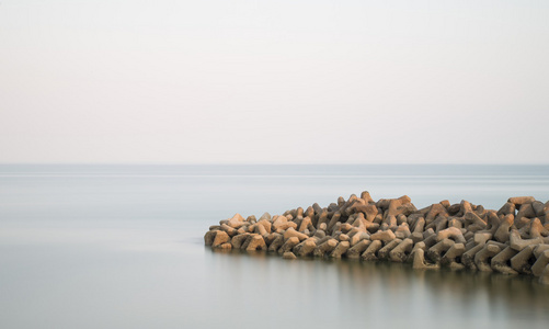 美丽的岩石露头进入平静的海面的平静景色