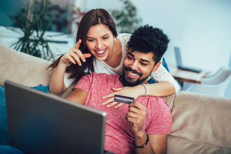 男子使用笔记本电脑和妇女持有信用卡在家里, 网上购物的概念