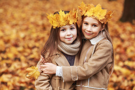可爱的两个小妹妹拥抱在秋季公园