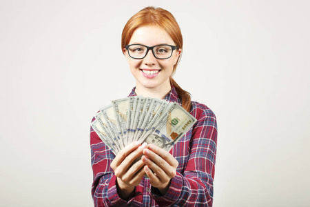 年轻漂亮的红发女人的肖像, 拿着一大把的钱持有100美元的栈像风扇.