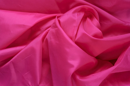 粉红色的合成衬里织物与褶皱。皱巴巴的床单或衣服背景