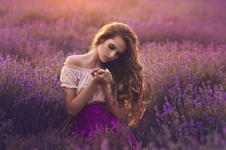 日落时在薰衣草地里的年轻女子。一个美丽的女孩在薰衣草花的肖像