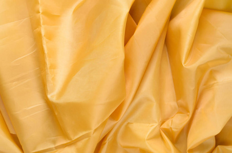 黄色合成衬里织物与褶皱。皱巴巴的床单或衣服背景