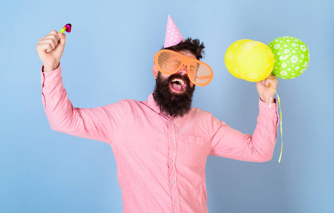 男人用胡子和胡子在快乐的脸上持有空气气球, 浅蓝色背景。时髦的大眼镜庆祝生日。党的理念。人在党帽子与假日属性庆祝