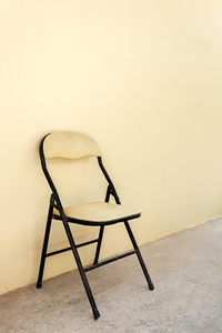 与米黄色墙的水泥地板上的旧椅子