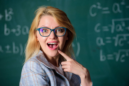老师想知道结果。你知道如何解决这项任务吗女戴眼镜聪明老师教室黑板背景, 特写。学校教育基础知识。解决数学任务